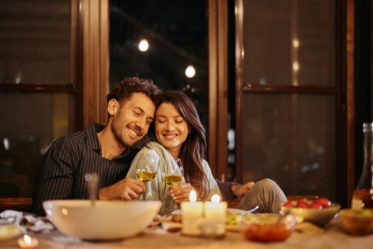 Happy couple in love toasting during a meal at dining table.