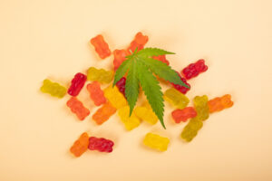 thc jelly candies, cannabis sweets drugs and green leaf on yellow background.