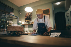 Asian man owner checking on financial bill when restaurant closed.